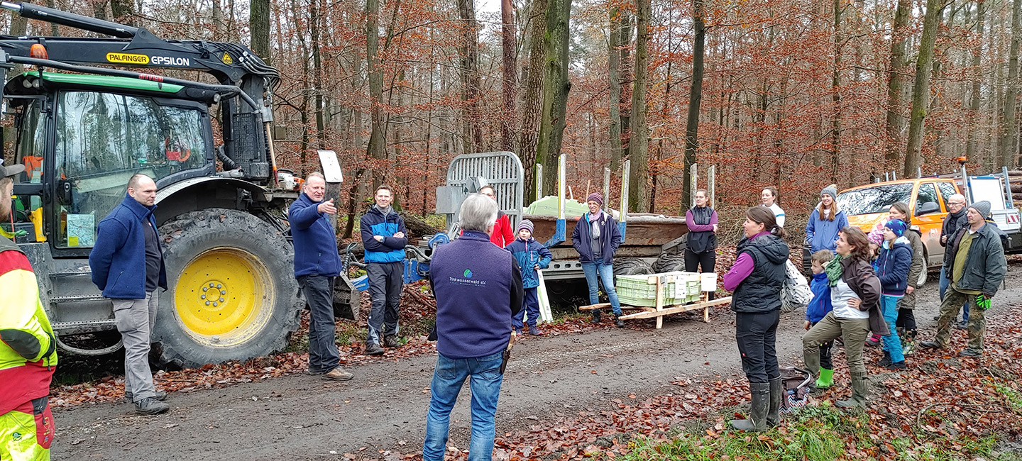 Personen stehen vor Traktor im Wald